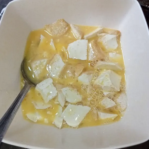 Kocok lepas telur, lalu masukkan potongan tahu dan aduk rata.