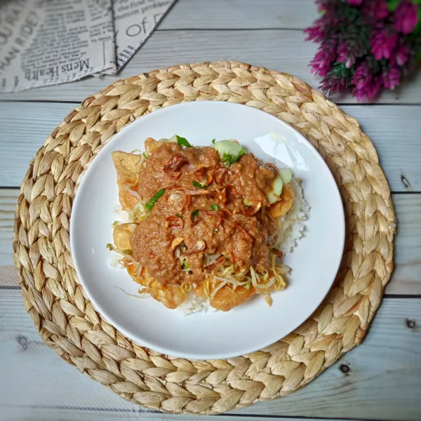 Penyajian, tata nasi atau lontong didasar piring, lalu letakkan telur tahu dadar, tauge, timun dan seledri, siram dengan kuah kacang dan taburi bawang merah goreng, sajikan.