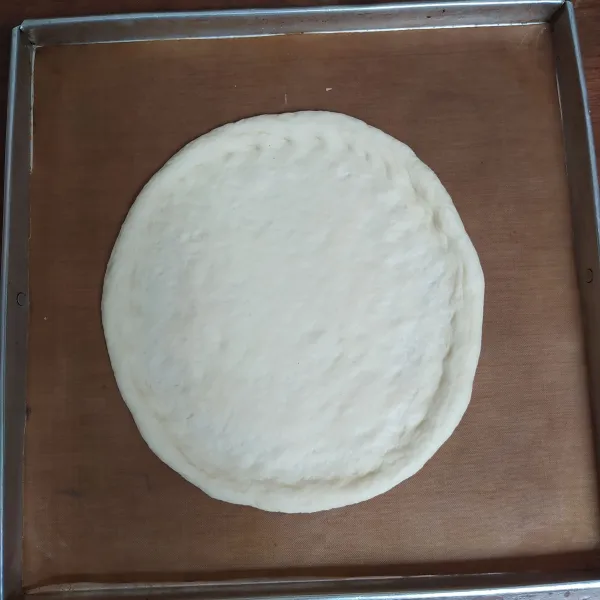 Pindahkan ke loyang yang sudah diolesi margarin atau dialasi parchment paper anti lengket. Rapihkan. Diameter pizza ini 20-22cm.