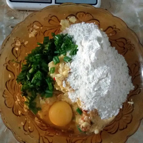 Lalu tambahkan telur, tepung terigu, daun bawang, seledri, garam dan kaldu bubuk ke dalam wadah berisi jagung yang sudah dihaluskan.