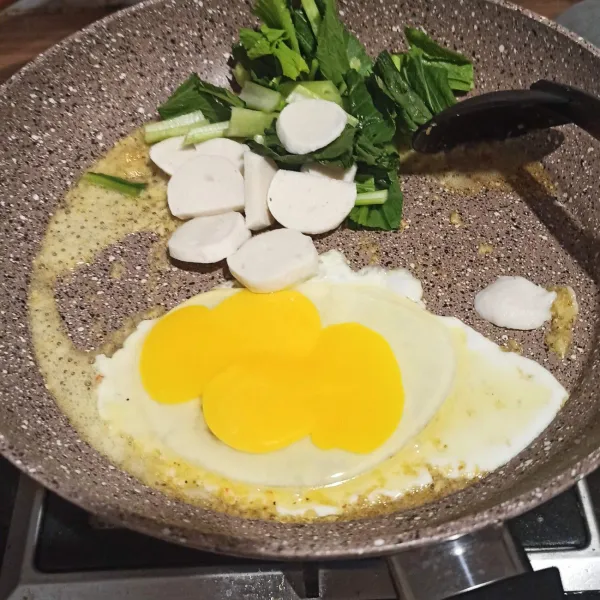 Masukkan bakso ikan, sayur dan telur. Tumis hingga layu.