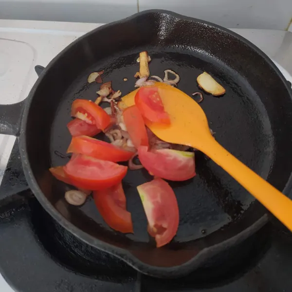 Tumis bawang merah dan bawang putih hingga harum. Masukkan tomat, tumis hingga layu.