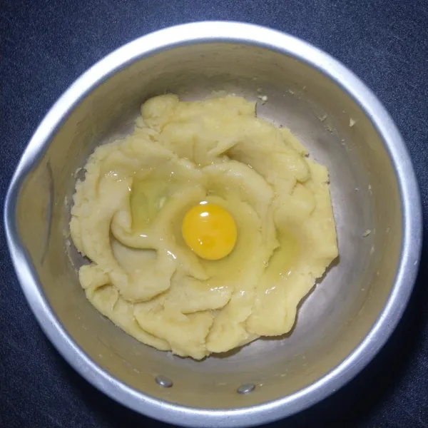 Setelah adonan dingin, tambahkan telur lalu uleni hingga tercampur rata.