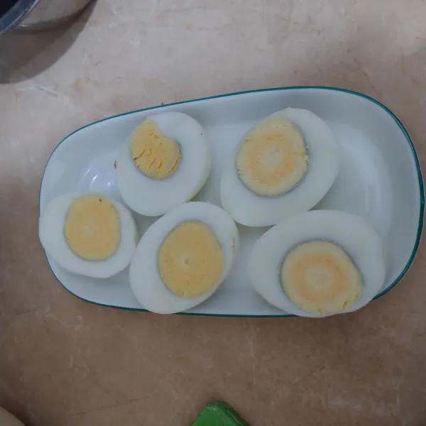 Rebus telur, biarkan dingin lalu kupas dan belah menjadi 2 bagian.