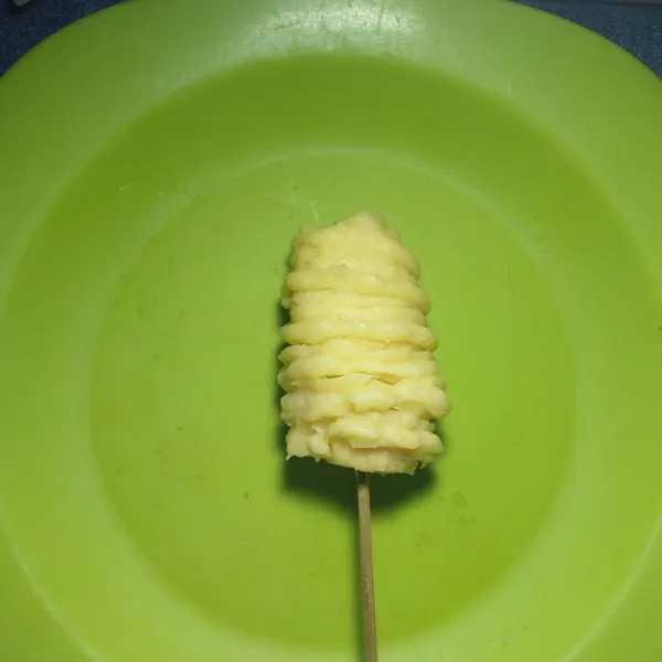 Lilit pisang dengan adonan churros dengan lapisi mengelilingi pisang sampai tertutup rata.