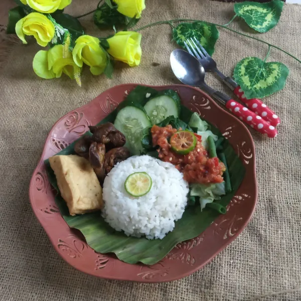 Tata nasi dipiring saji, beri tahu goreng, aati ampela goreng, irisan mentimun dan sayur rebus lalu siram dengan sambal. Sajikan.