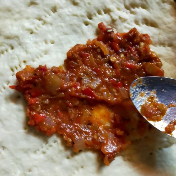 Pipihkan adonan diatas pan pizza, tusuk tusuk dengan garpu lalu beri saus secukupnya kemudian ratakan. Tata bulatan beruang dan bulatan pada pinggiran pizza. Beri toping sosis dan jagung manis secukupnya.