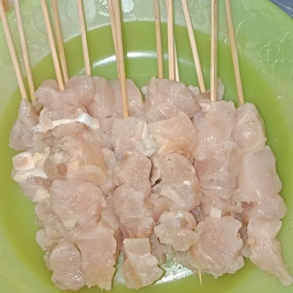 Susun potongan daging ayam ke tusukan sate.