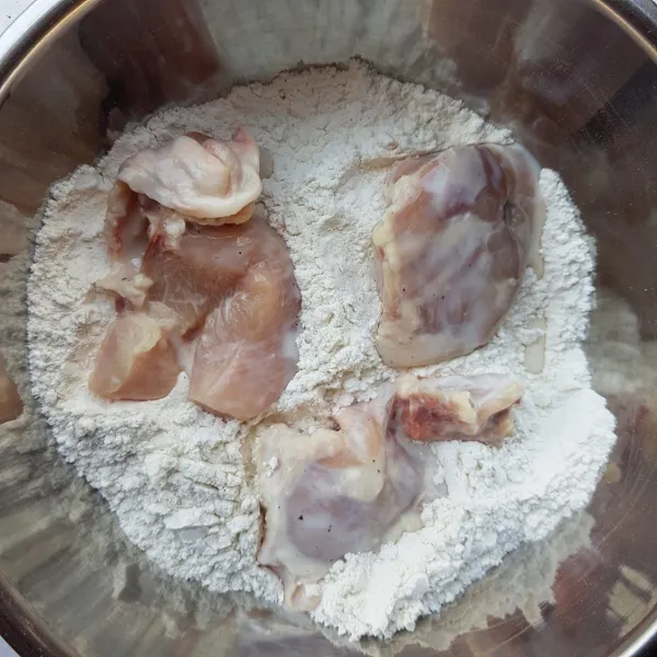 Keluarkan rendaman ayam dari dalam kulkas. Angkat beberapa potongan ayam dari rendaman, masukkan ke dalam wadah berisi bahan tepung. Balut semua bagian ayam dengan tepung hingga rata.