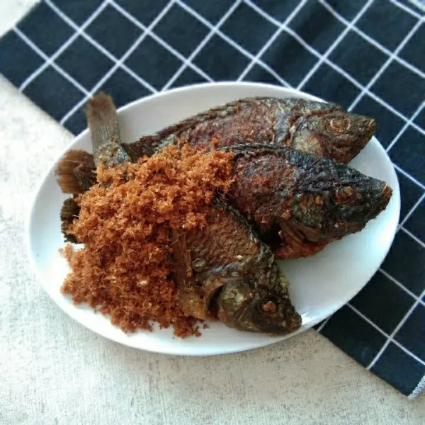 Salin ikan nila goreng pada piring, taburi dengan serundeng lengkuas.