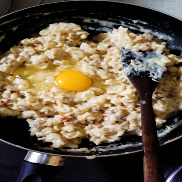 Masukkan telur perbutir, sambil terus diaduk agar tercampur merata. Setelah telur matang matikan api, pindahkan ke wadah aluminium dan beri toping keju