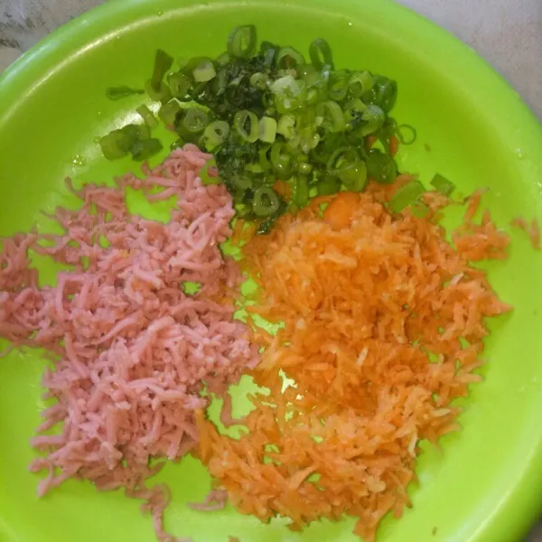 Cuci bersih wortel dan daun bawang. Iiris halus daun bawang, parut wortel dan sosis dengan parutan keju.