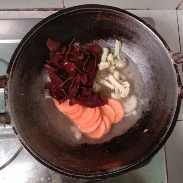 Masukkan wortel, brokoli atau bisa dengan kembang kol, dan jamur kuping. Aduk rata dan tunggu hingga semua bahan empuk.