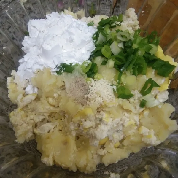 Tuang kentang tahu pada mangkuk, tambahkan tepung tapioka, garam, kaldu jamur, merica bubuk dan bawang daun, aduk rata.
