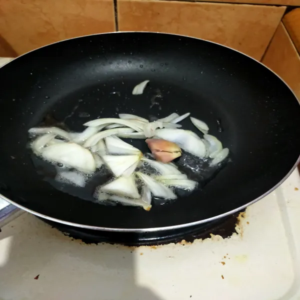 Panaskan minyak kelapa, lalu masukkan bawang bombay dan lengkuas. Masak hingga sedikit layu.
