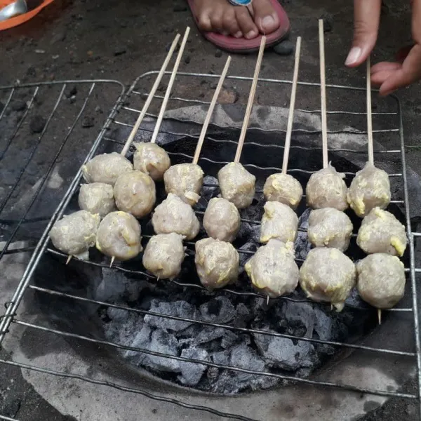 Bakar pentol tusuknya di atas bara arang.