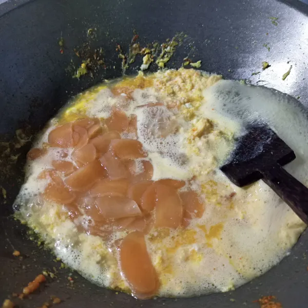 Sisihkan bumbu ke pinggir wajan, masukkan telur, aduk-aduk hingga matang. Masukkan air, kerupuk udang rebus. Koreksi rasanya.