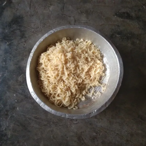 Rebus mie kuning setengah matang dan tiriskan. Lalu bilas dengan air dingin saat mie masih panas untuk menghentikan proses pematengan.