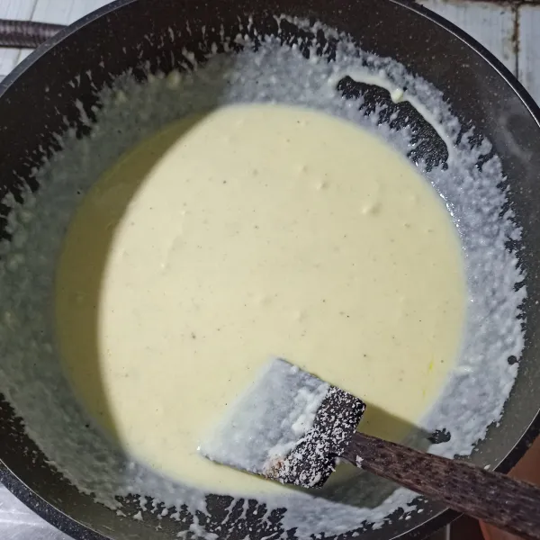Masukkan tepung terigu, aduk cepat kemudian masukkan susu cair putih. Masukkan keju parut, garam, oregano dan lada hitam bubuk. Aduk-aduk, jangan lupa koreksi rasanya.
