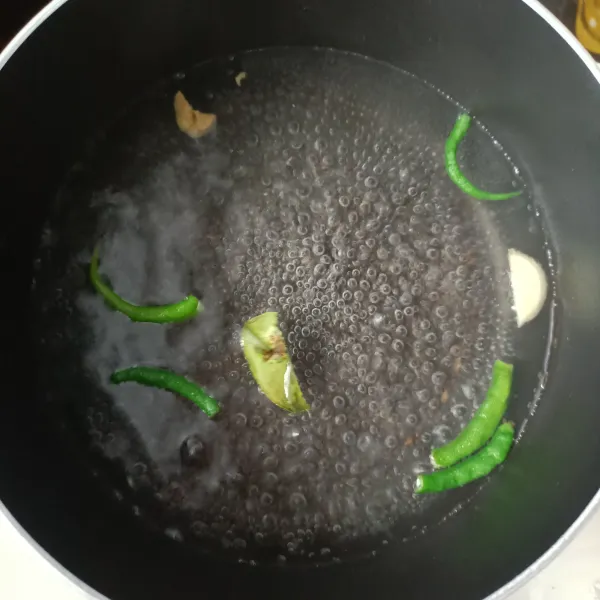 Didihkan air, lalu masukkan bawang putih, cabai hijau, dan daun jeruk.