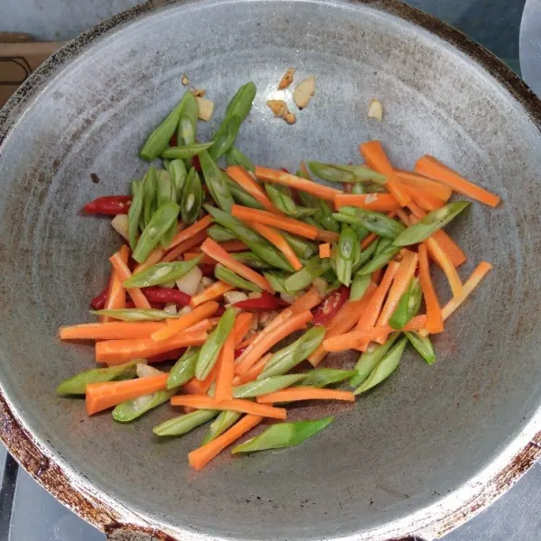 Masukkan wortel, buncis dan air. Aduk rata. Masak sampai layu.