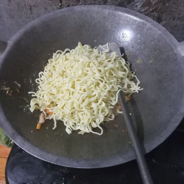 Masukkan mie, kemudian aduk rata. Lalu kecilkan api.