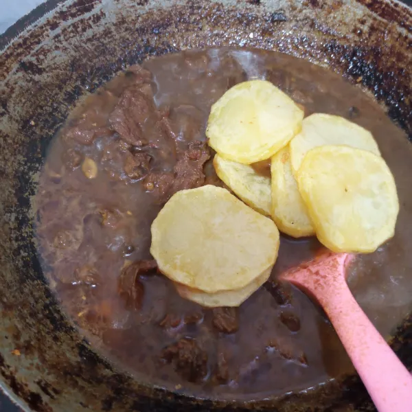 Setelah air mulai menyusut, masukkan kentang, aduk pelan agar kentang tidak hancur.