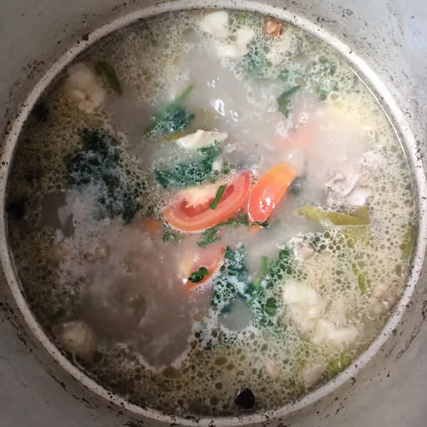 Tambahkan garam, gula, dan kaldu bubuk. Masukkan juga tomat dan daun sup. Kemudian aduk rata dan koreksi rasa. Sajikan dengan bihun dan bawang goreng.