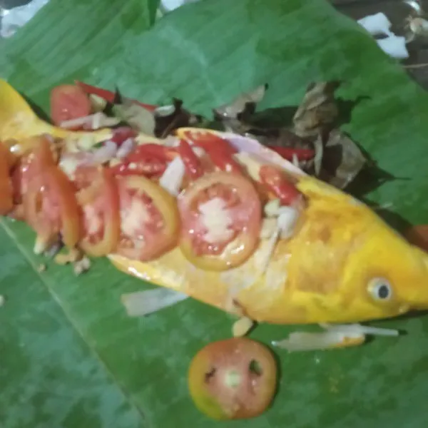 Siapkan daun pisang, masukkan ikan lalu tambahkan daun salam dan tomat, bungkus.