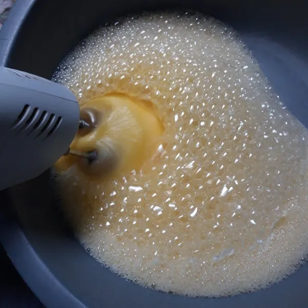 kocok telur dan gula dengan kecepatan tinggi hingga mengembang berwarna putih, kemudian masukkan soda kue dan baking powder serta margarin, kocok rata.