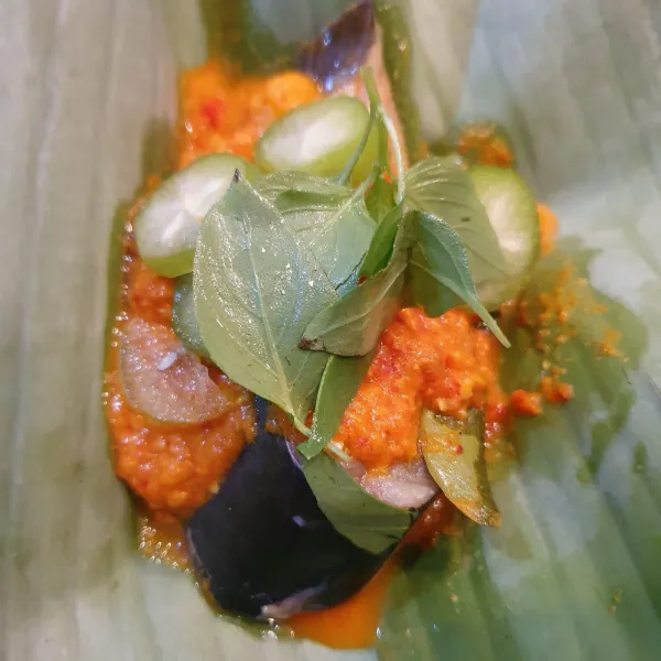 Siapkan daun pisang, ambil sepotong patin berserta bumbu. Bungkus dengan bantuan lidi.
