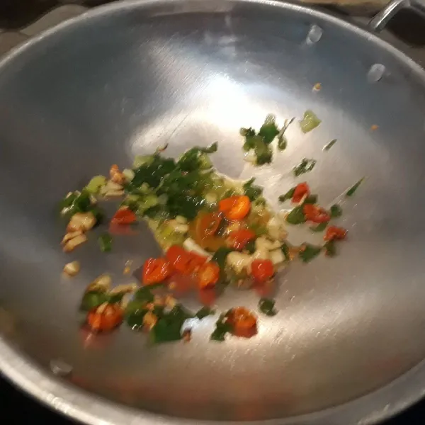 Panaskan minyak, lalu tumis bawang putih cincang, daun bawang, dan irisan cabai rawit merah.