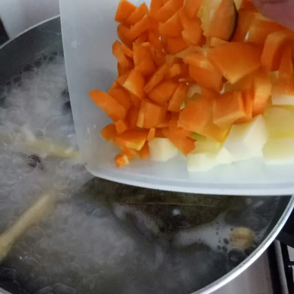 Masukkan kentang dan wortel, lalu tambahkan air.