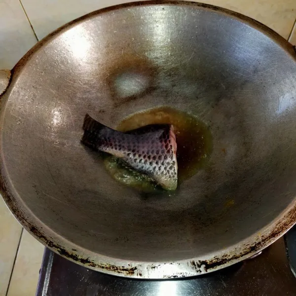 Bersihkan ikan nila dari sisik dan isian perutnya. Cuci bersih lalui bumbui dengan lada dan garam. Goreng ikan nila hingga matang.