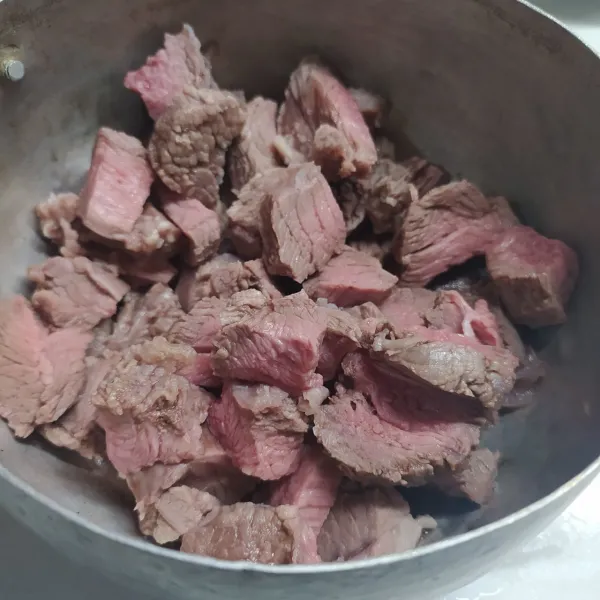 Rebus daging di air mendidih sampai keluar busa. Buang air rebusan, potong-potong daging.