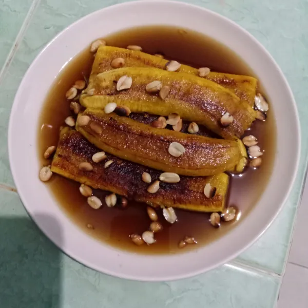 Tata pisang di piring, siram dengan kuah gula merah, taburi kacang sangrai dan sajikan.