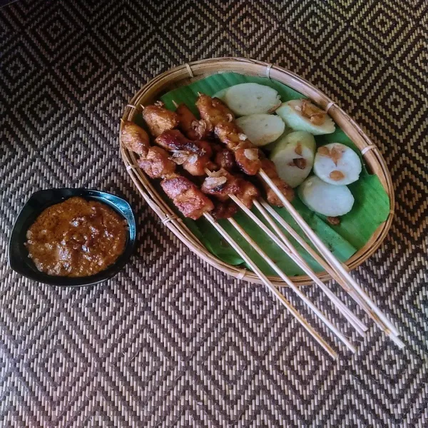 Sajikan sate ayam Makassar dengan saus bumbu dan lontong. Taburi bawang merah goreng jika suka.