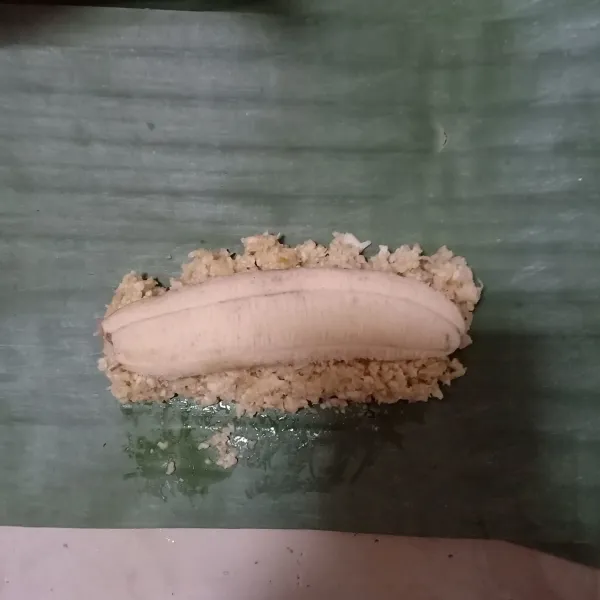 Ambil daun pisang, isi dengan 1sdm adonan , tambahkan pisang yang telah dibelah.