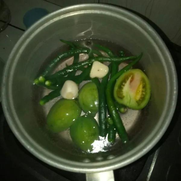 Siapkan panci dan didihkan air. Rebus cabe, tomat dan bawang putih sampai matang. Angkat dan tiriskan.
