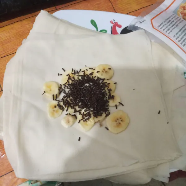 Ambil selembar kulit lumpia, beri potongan pisang dan 1 sdm meises coklat.