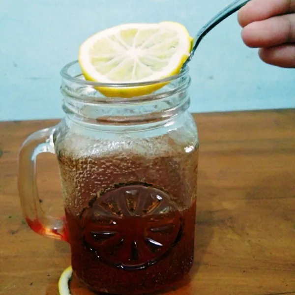Tambahkan irisan lemon ke dalam teh.
