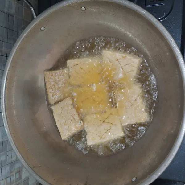 Goreng tempe yang sudah dibumbui dengan garam hingga matang.