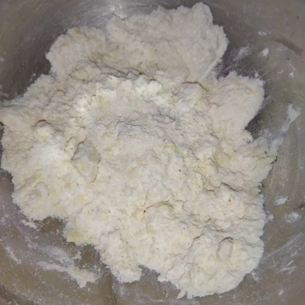 lalu masukkan tepung terigu dan gula halus aduk dengan menggunakan spatula atau dicacah dengan pisau pastry, hingga adonan menggumpal.