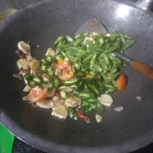 Masukkan buncis, tomat dan cabai hijau besar. Tuang air. Aduk rata. Masak hingga buncis layu.