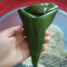 Membuat lontong, potong daun selebar ±25-30 cm per lembarnya. Layukan di api kompor atau dijemur, cuci bersih. Lalu buat kerucut, beri semat di sampingnya. Isi dengan beras yang sudah dicuci dan dikeringkan sebelumnya, isi sebanyak ±2 sdm beras. Tutup bagian atas kerucut, lalu kunci dengan semat lidi.