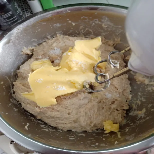 Lalu masukkan mentega dan garam dan uleni kembali hingga kalis.  Tutup adonan dengan plastik dna dimkan hingga mengembang 2 kalinya