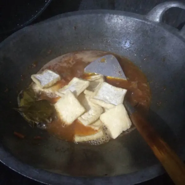 tuang air, bumbui dengan garam, kaldu bubuk dan kecap manis. aduk rata. masukkan tahu goreng.