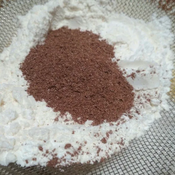 Tambahkan tepung terigu, tepung tapioka, tepung beras dan minuman serbuk coklat dengan disaring.