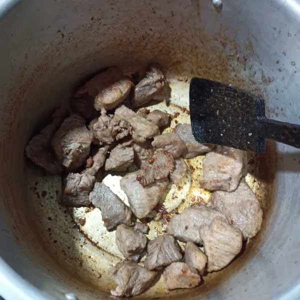 Panaskan 1 sendok sayur minyak goreng di panci presto, kemudian masukkan daging sapi. Aduk-aduk sampai air yang terkandung dalam daging mengering dan kecokelatan. Kemudian angkat.