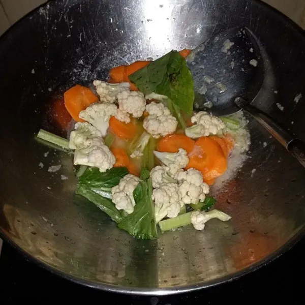 Masukan wortel dan air. Masak hingga wortel matang. Masukan bunga kol dan caisim.